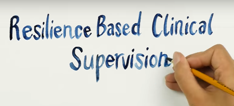 an image of the words 'Resilience Based clinical supevision' being painted by a single hand in blue ink